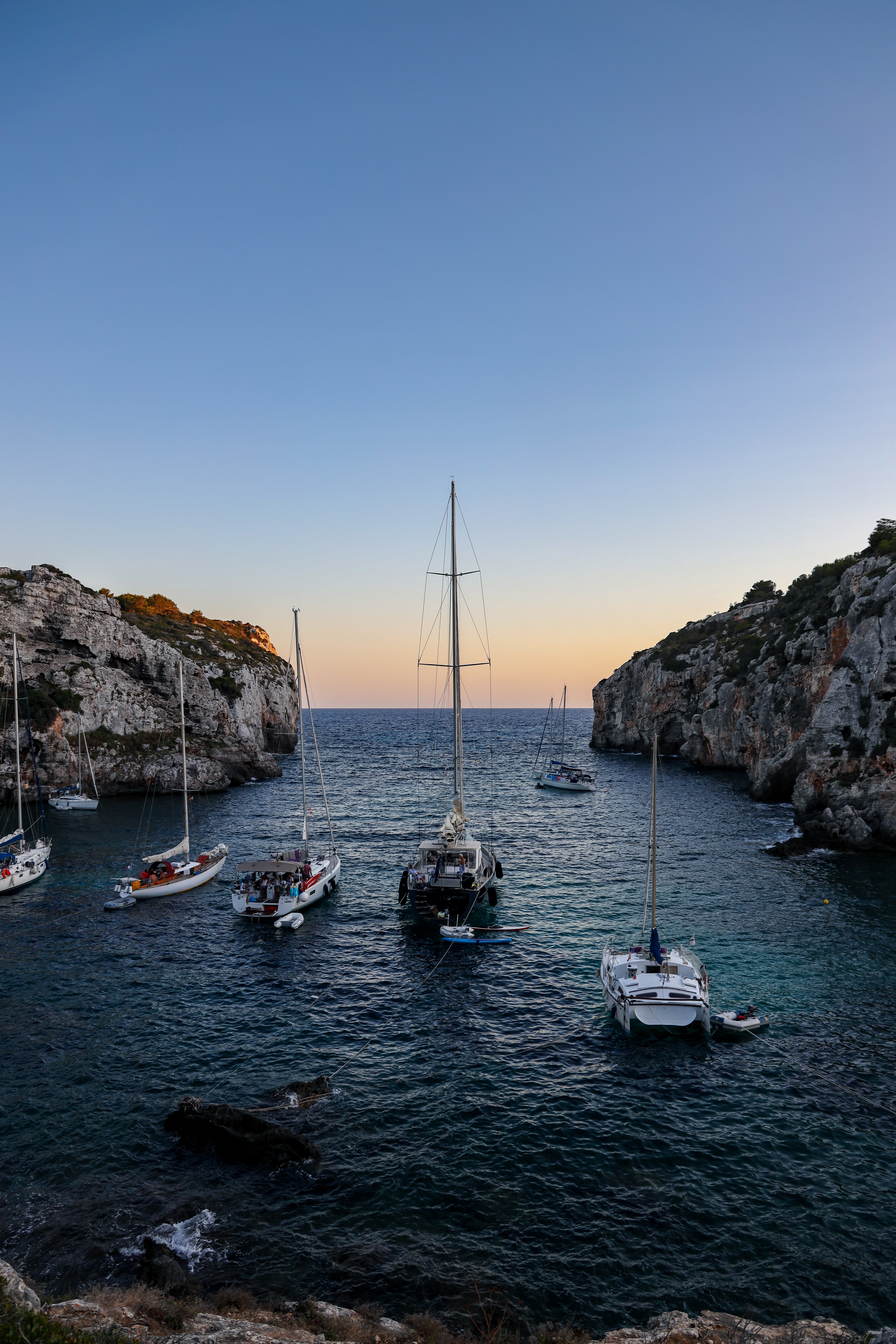 Yachts anchored in a quiet cove at dusk